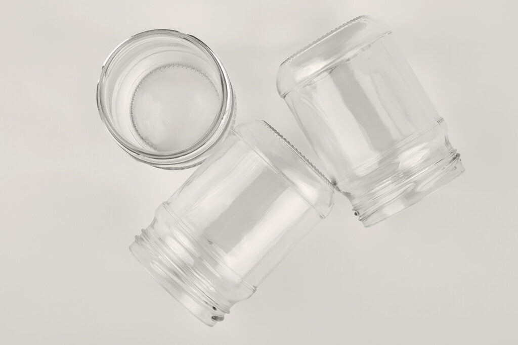 Three clear glass jars with their labels removed on a white surface, shot from above.