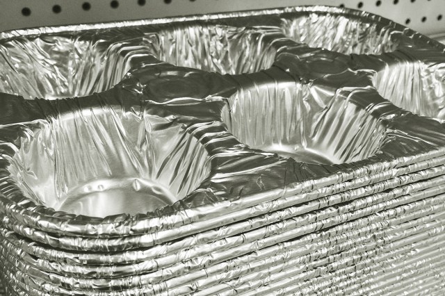 Close-up shot of disposable, aluminum muffin pans. There are about a dozen of them stacked on top of each other.