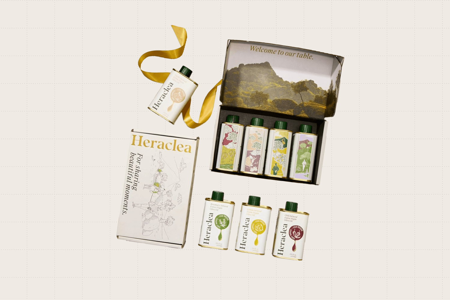 Open gift box showing four, 5.9-ounce bottles of heraclea extra virgin olive oil. The box shows a mountain landscape and the bottles are metal with colorful illustrations on them.