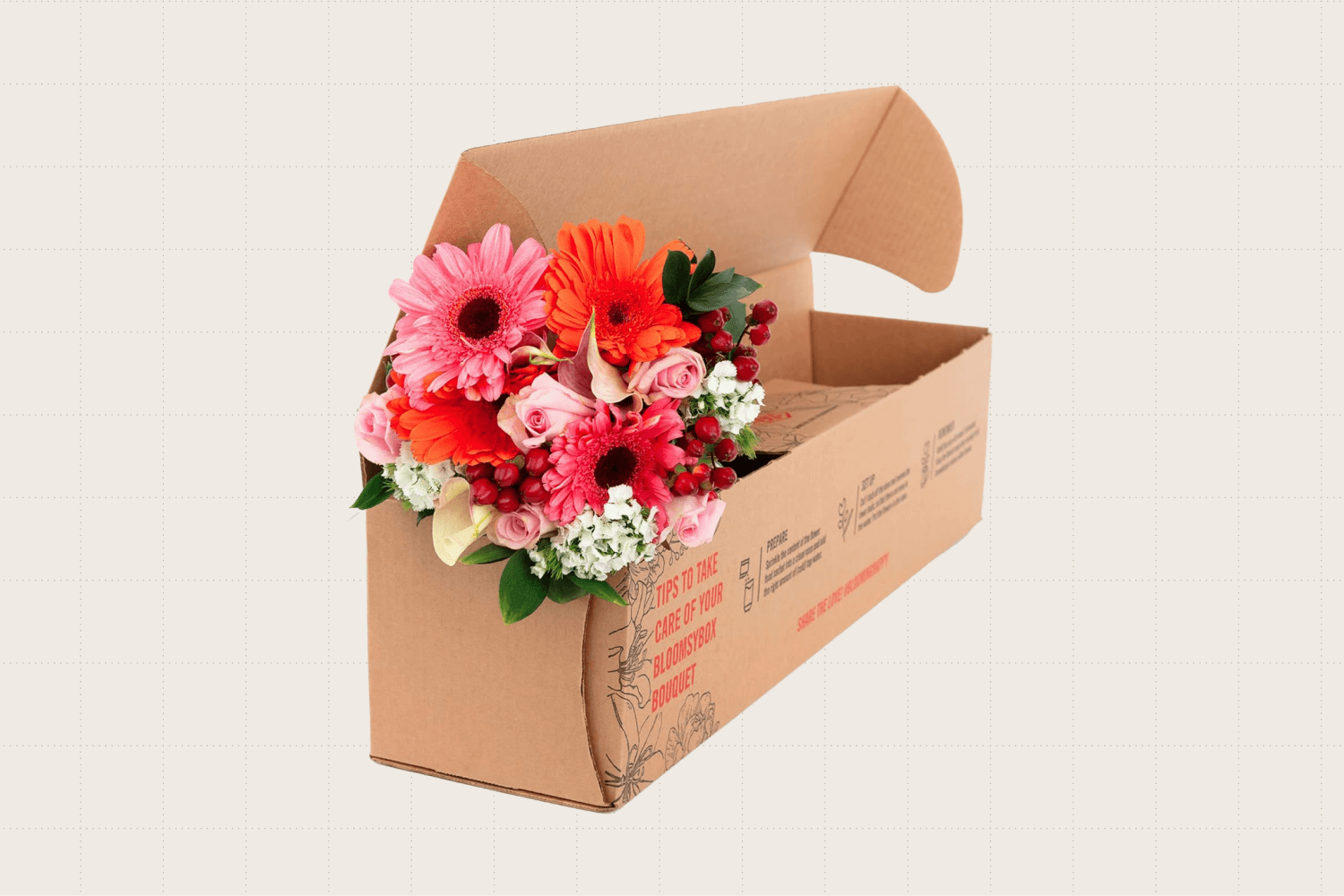 A BloomsyBox bouquet shown in its shipping box. The bouquet has shades of pink, red, white, and orange.