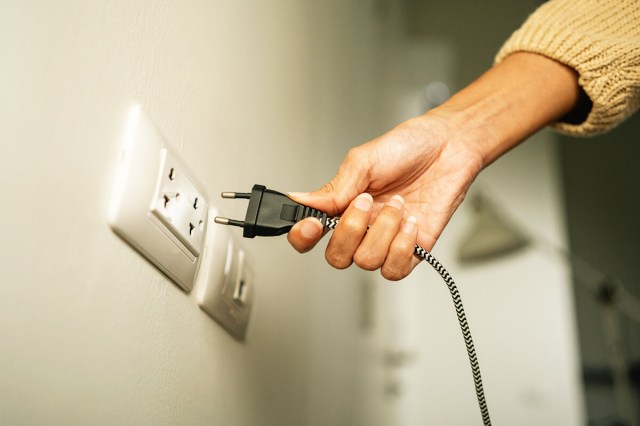 Anonymous person unplugging an electronic from the wall.