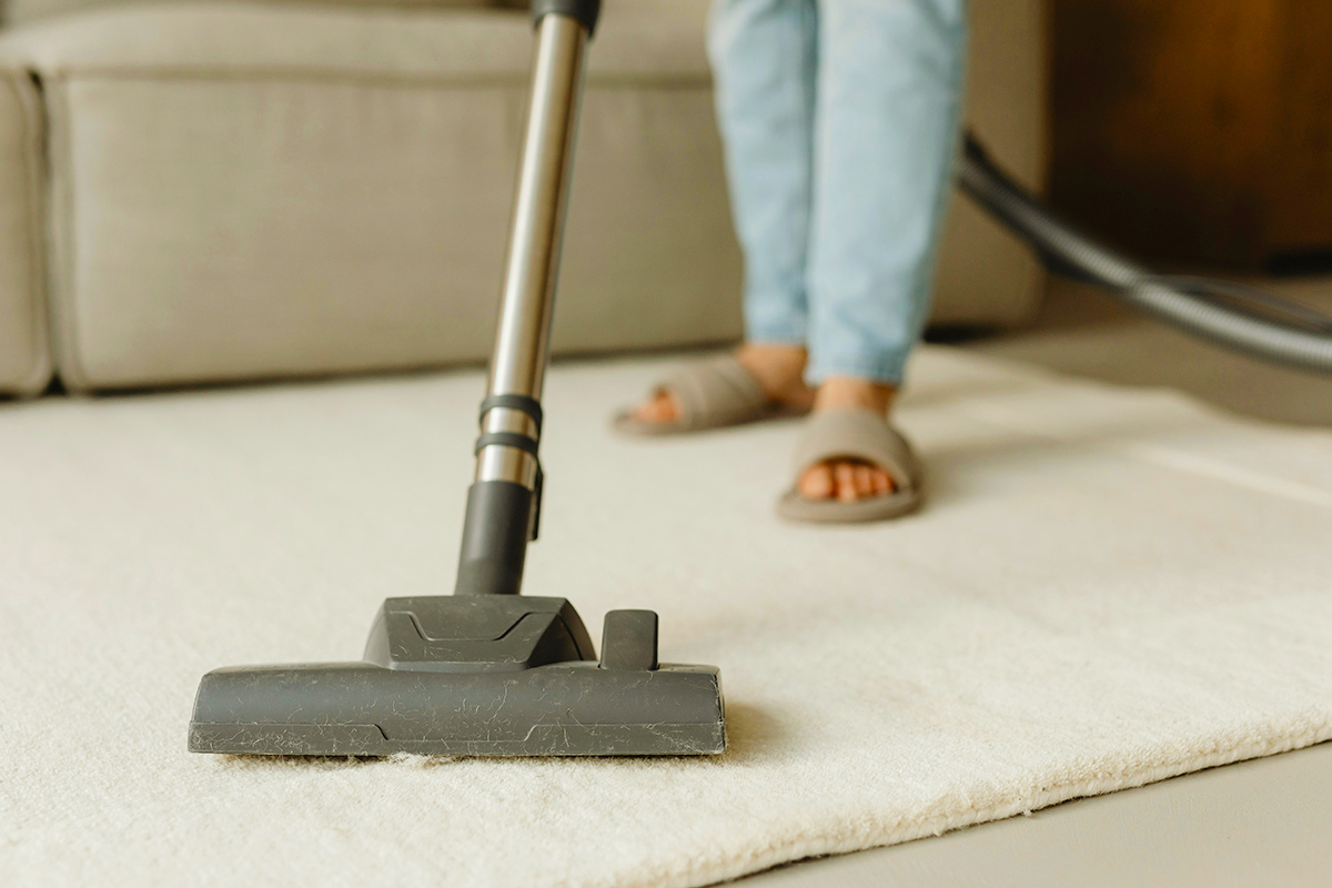 Person cleaning carpet with a vacuum