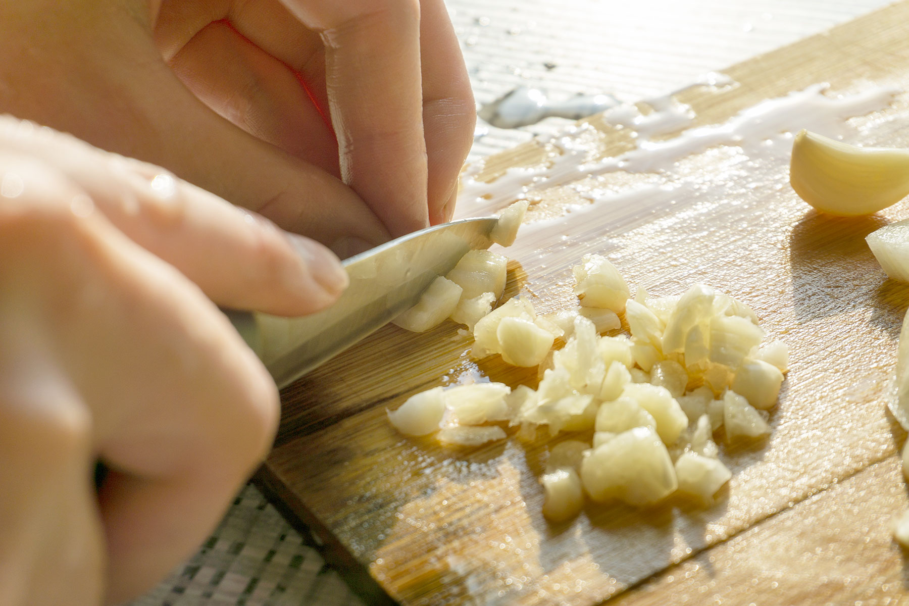 Close up of a person cutting garlic with a knife