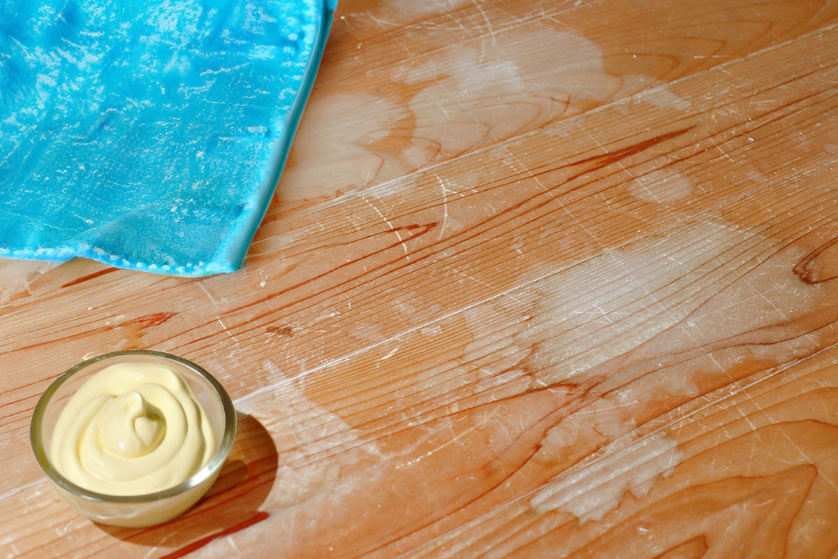 Wood water stains with a dish rag and cup of mayonnaise