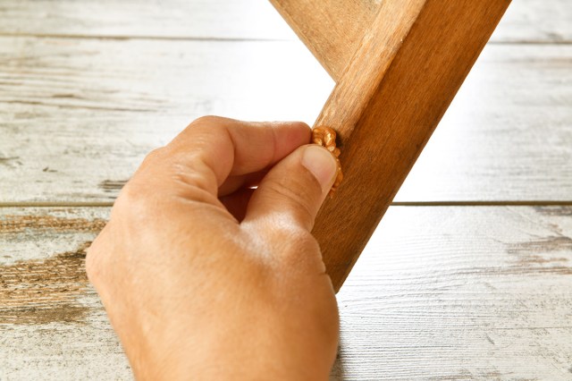 Anonymous person using a walnut to erase a scratch on a piece of wood furniture.