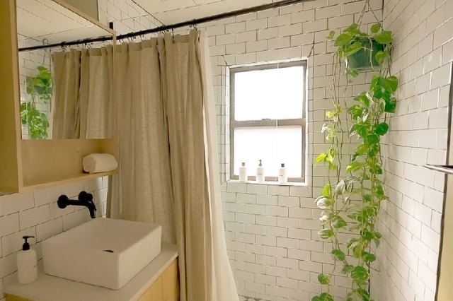 A modern-looking bathroom with a tub/shower combination. The walls are covered in white subway tile and there's a beige shower curtain paired with a white shower curtain liner.