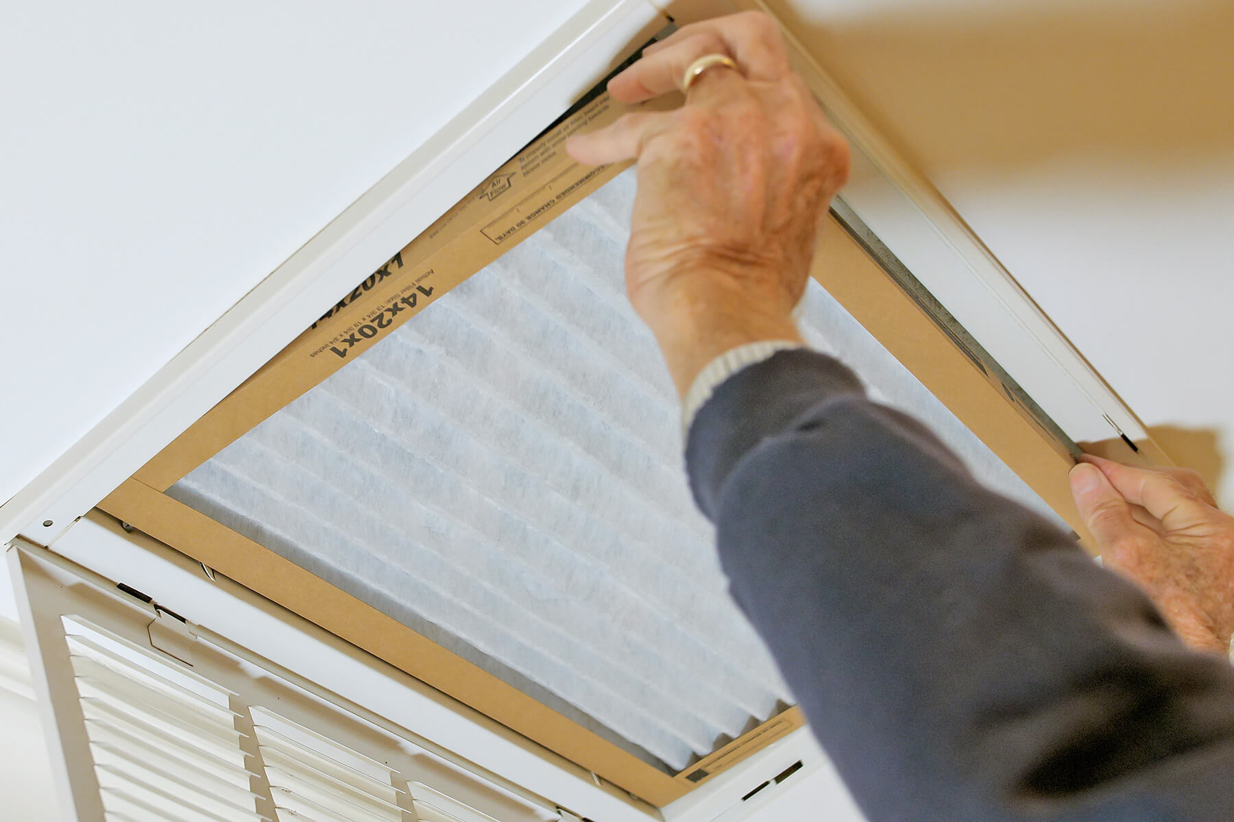 Anonymous person replacing an air filter in a ceiling duct.